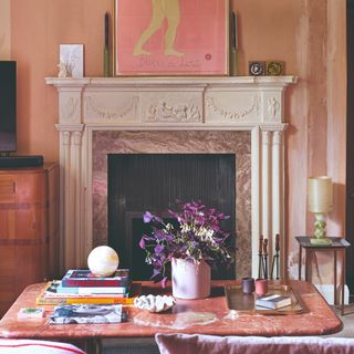 A living room with earthy pink walls and a terracotta-coloured stone coffee table