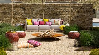 Outdoor living room area with focal fire pit with footstools for extra seating and traditional rattan sofa