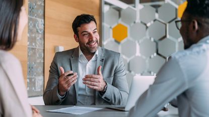 Adviser cheerfully talking to two clients in a meeting room