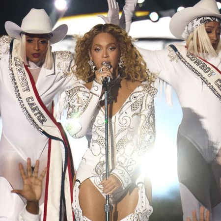 Beyonc&eacute; sings into a mic stand on stage with two backup dancers in white Western costumes, during Netflix's 'Beyonc&eacute; Bowl.'