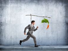A man in a suit chases a carrot that is connected to his back.
