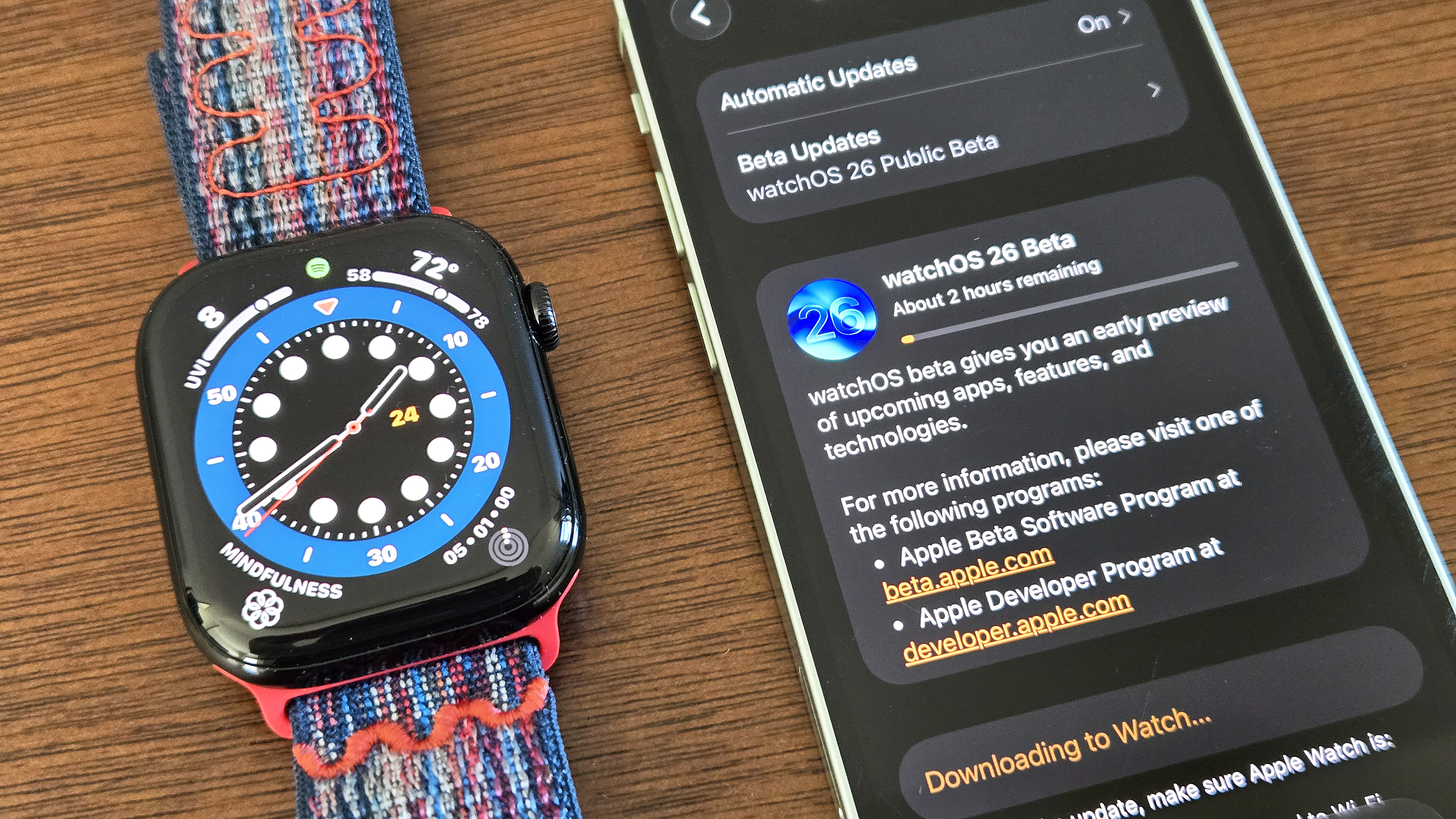 Close-up of the installation process for watchOS 26 showing an Apple Watch Series 10 and iPhone 12 Mini