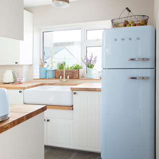 kitchen room with blue fridge and white wall with sink