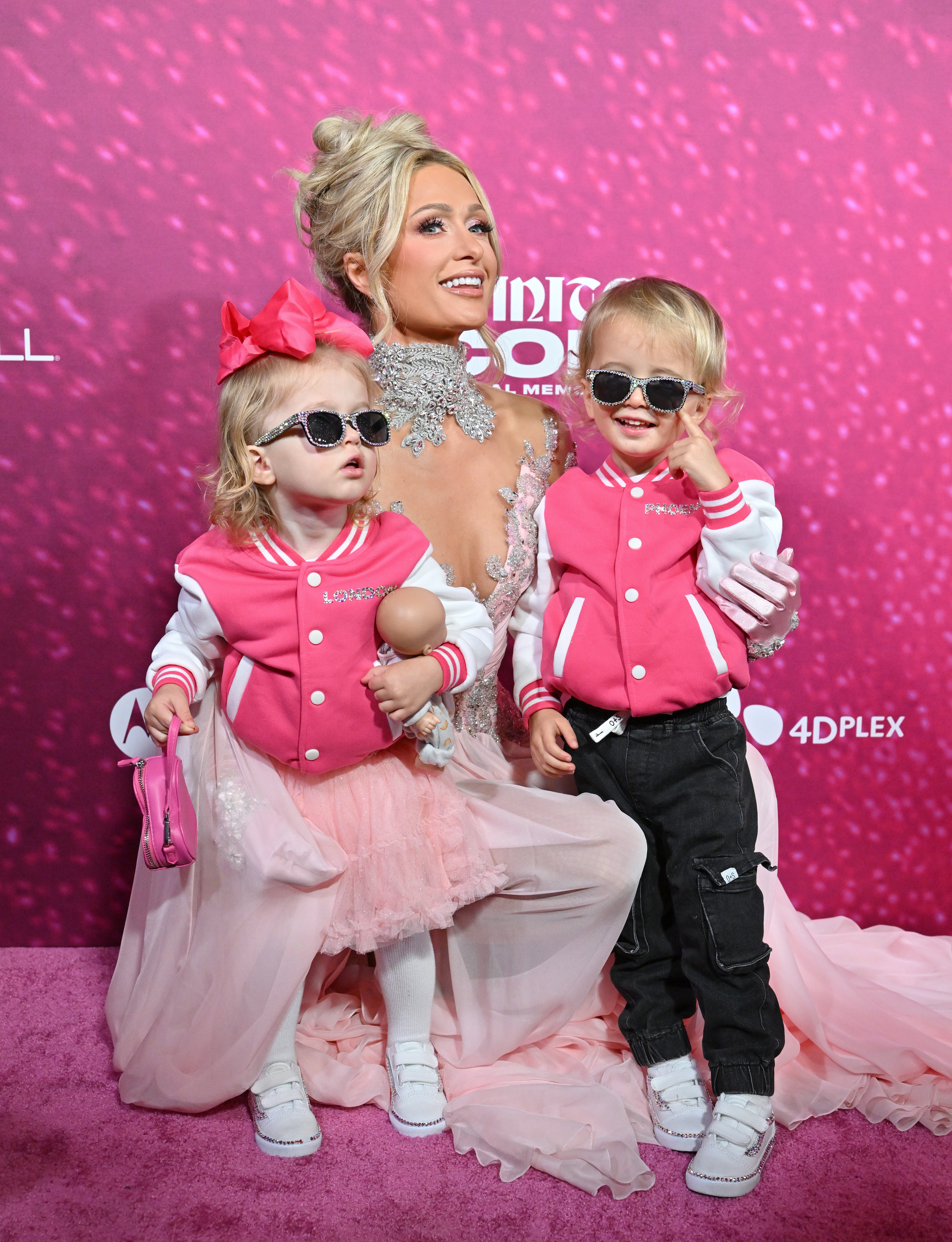 Paris Hilton, London Reum and Phoenix Reum posing on a pink carpet in pink outfits