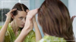 Woman in green dressing gown checking scalp in mirror for alopecia