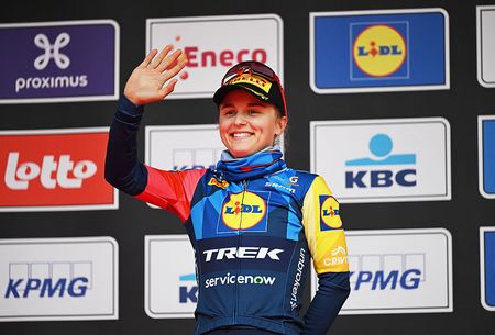 Fleur Moors of Lidl-Trek stands on the podium of In Flanders Fields 2026, smiling and holding one arm up, waving to the crowd