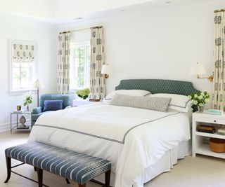 white bedroom with blue accent furniture and headboard and stacks of decor accessories