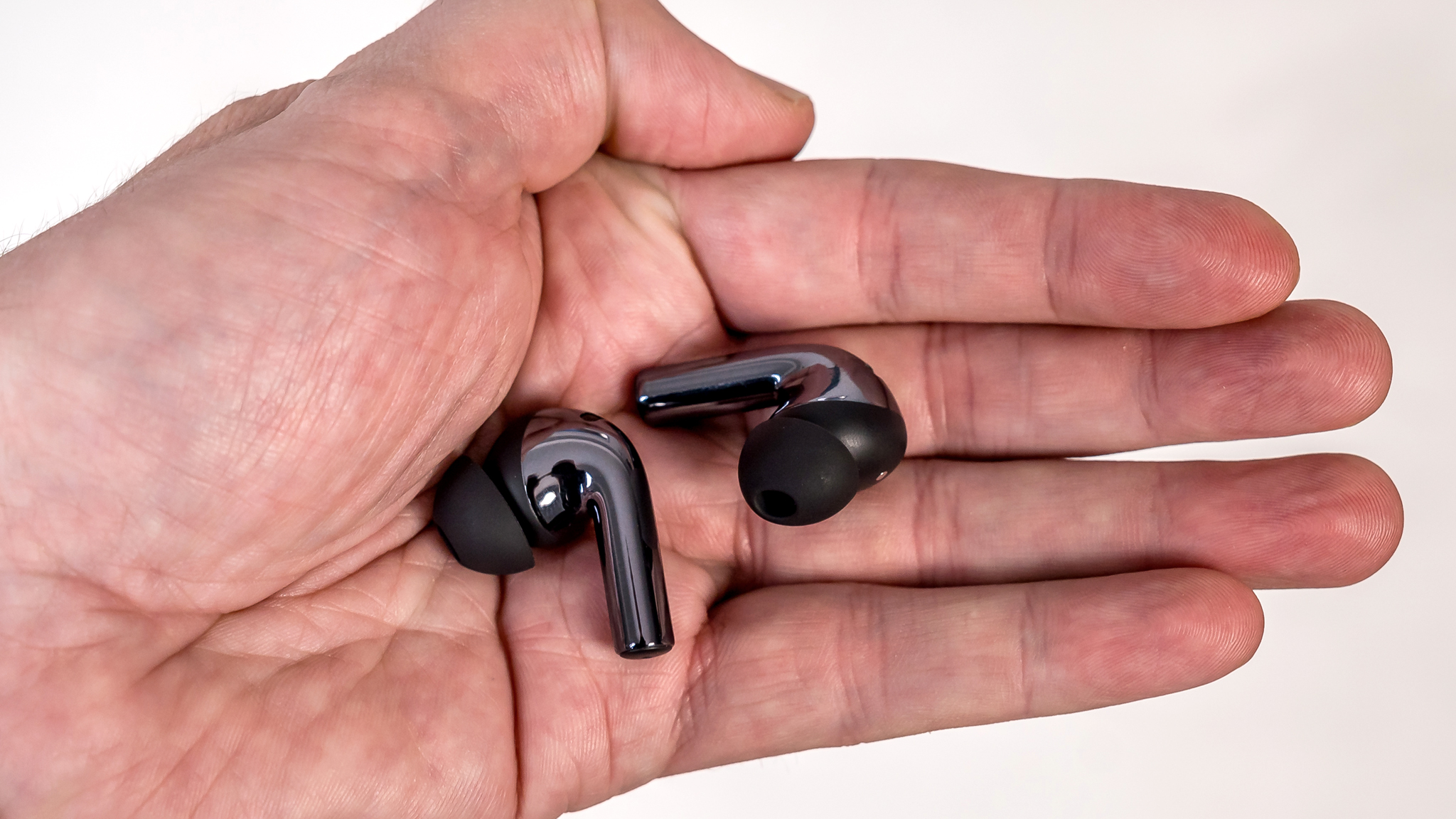 OnePlus Buds 3 earbuds in hand.