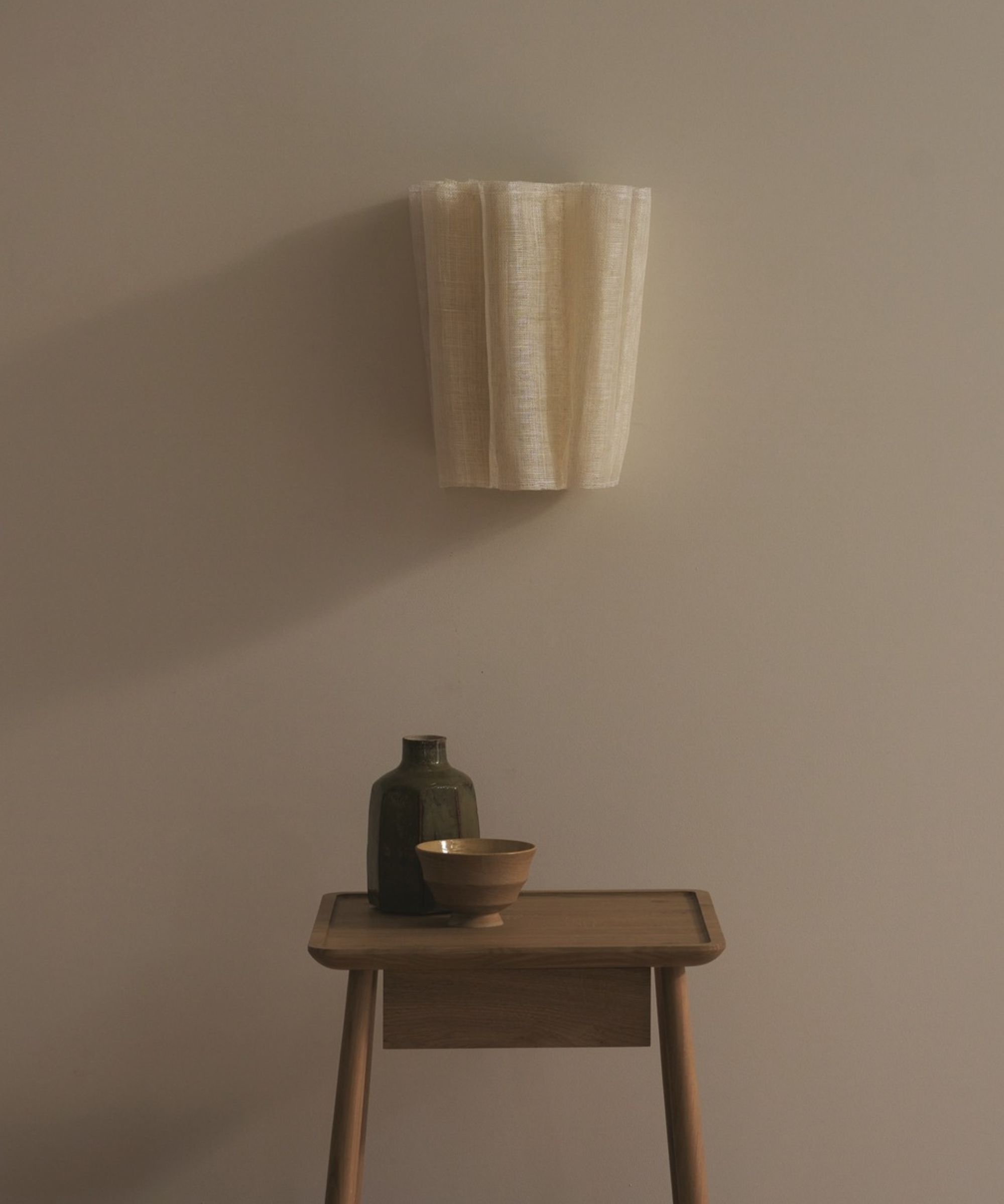 fabric woven wall-light with a side table with vase on it