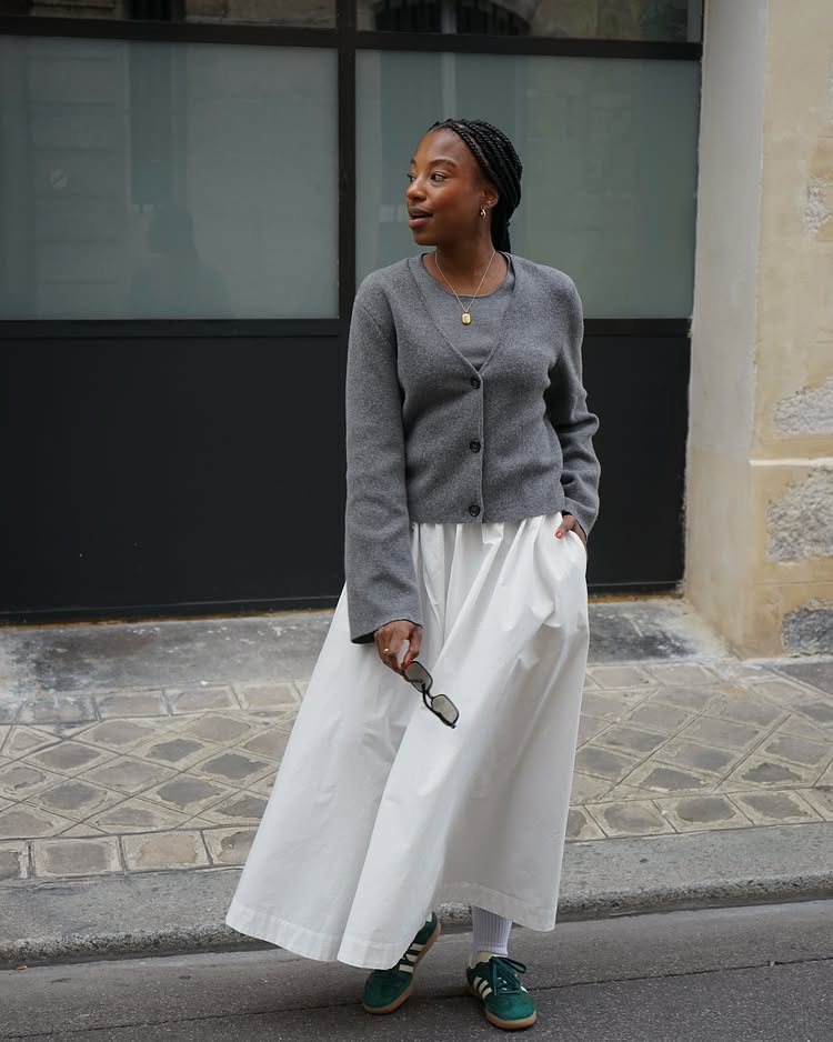 @taffymsipa wears a grey cardigan, white skirt and green trainers