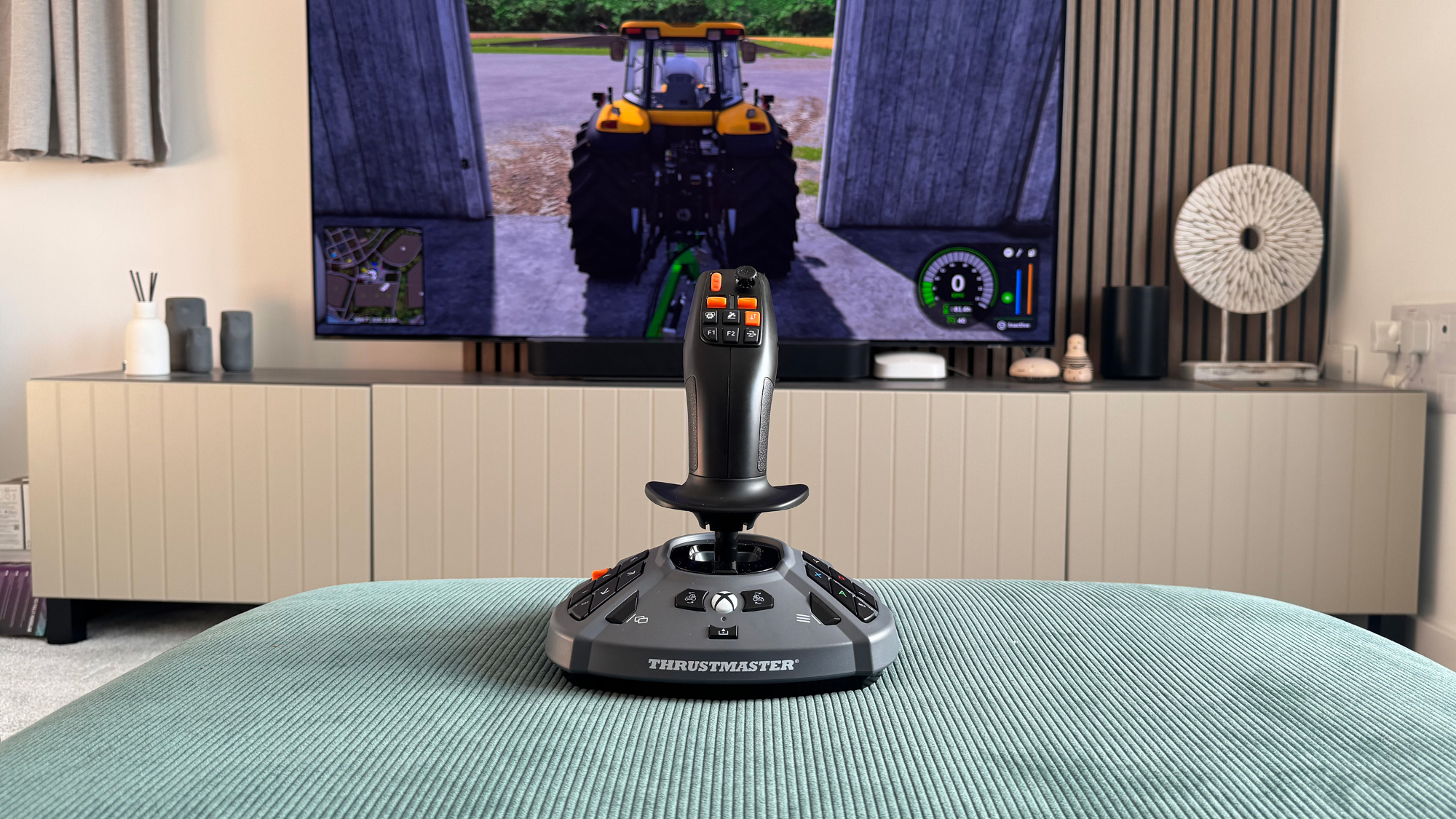 The Thrustmaster SimTask Farmstick X in front of a gaming TV