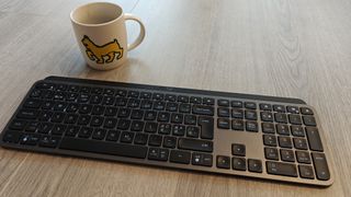 Logitech MX Keys S ja kahvikuppi puisella lattialla