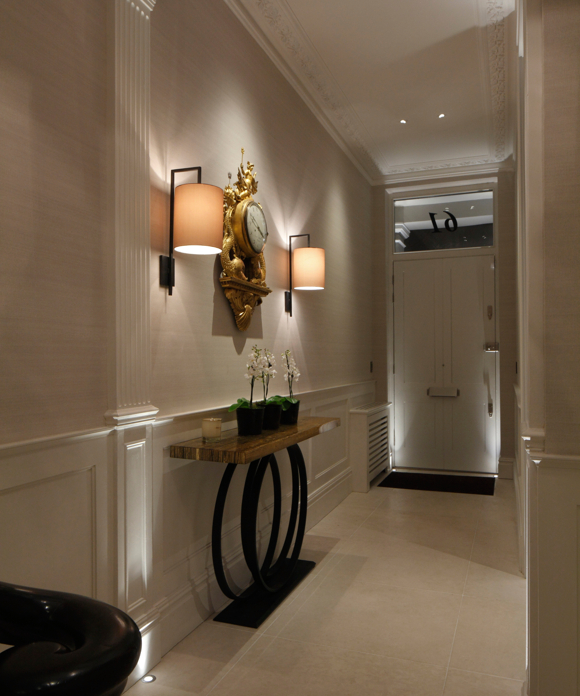 hallway with shaded wall lights as well as small inset floor lights by front door and small spots in ceiling