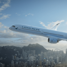 A Cathay Pacific plane flying over the top of a city