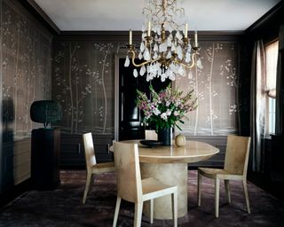 dining room with dark gray tree covered wallcovering, panelled walls, glass chandelier, and parchment oval table and chairs
