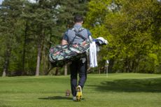 A golfer carrying a set of golf clubs