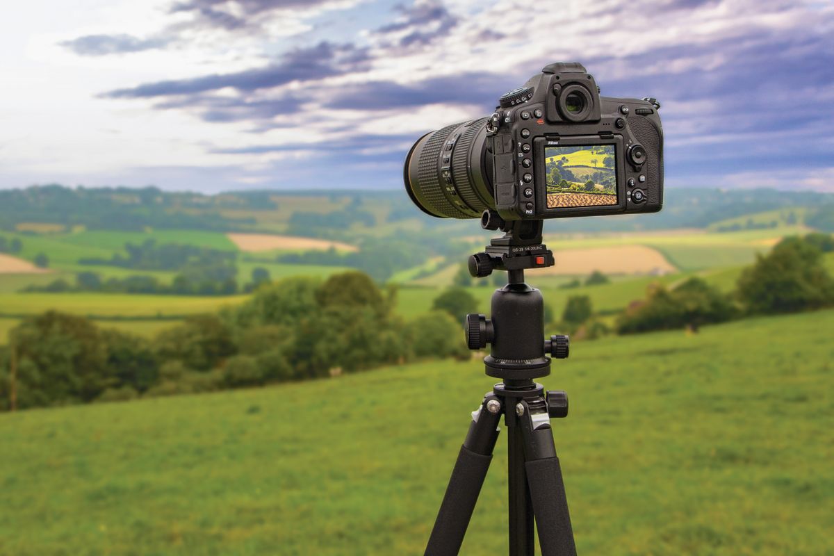 Nikon D800 and 80-400mm lens on a tripod against a backdrop of a cloudy landscape