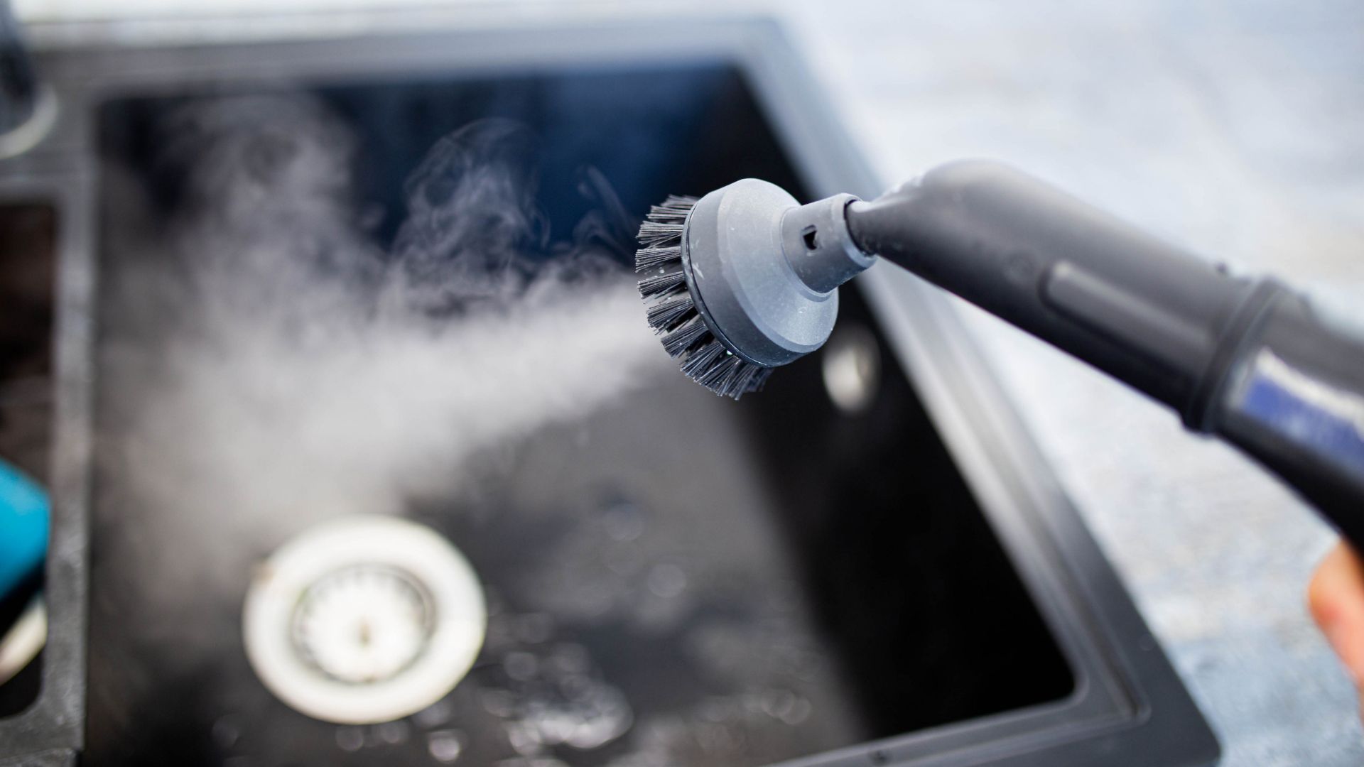 steam cleaner being used on a kitchen sink