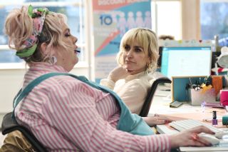 Ruby (Jayde Adams) sits at her desk in the call centre, leaning back with her eyes closed, while Vicki (Katherine Kelly), sitting facing her in an office chair, watches her intently