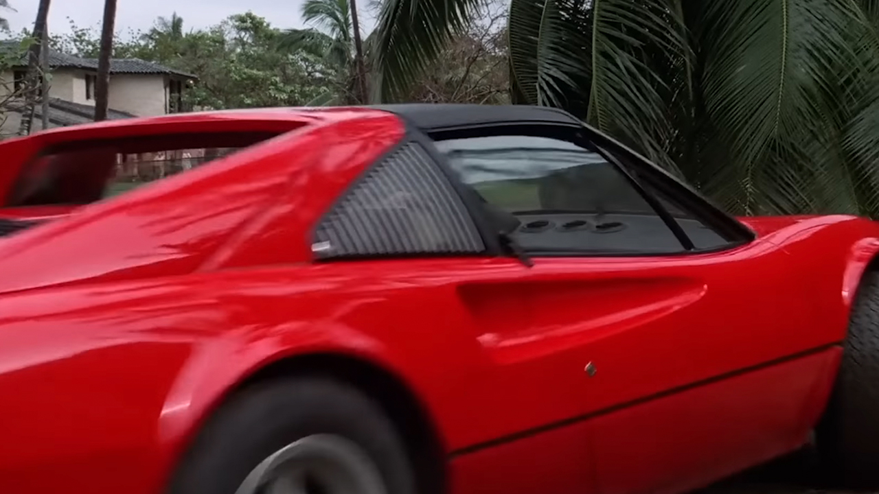 The red Ferrari from the side, speeding away.