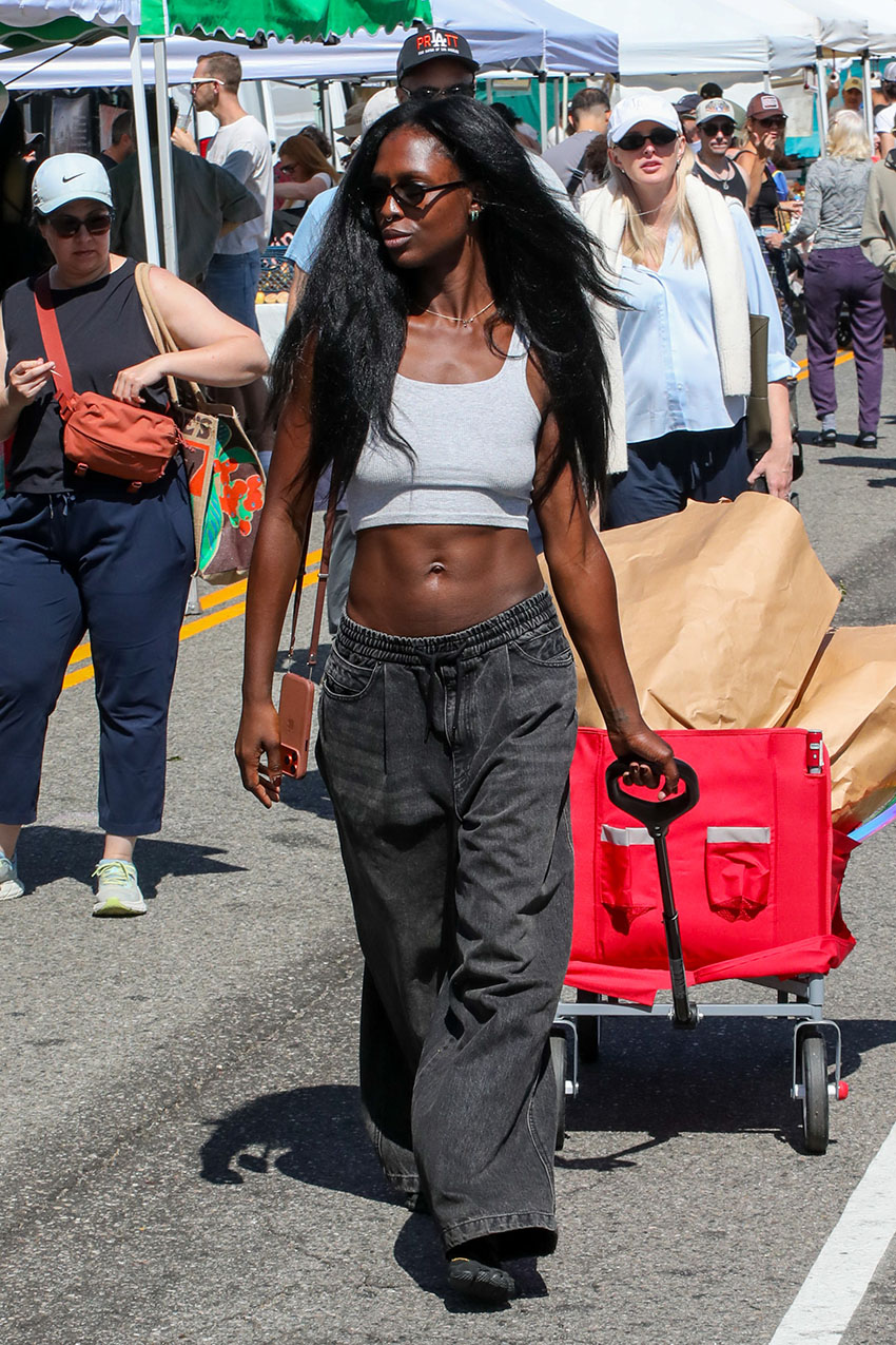 Jodie Turner-Smith wearing a gray tank top, gray denim drawstring jeans, and black Vibram fivefinger shoes