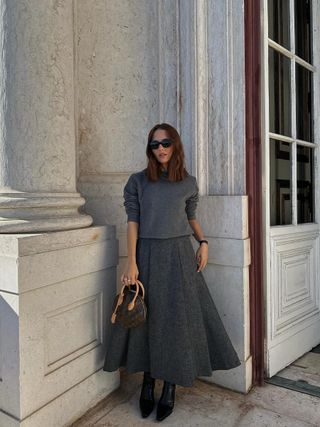woman wearing gray full skirt with black ankle boots and matching gray sweater