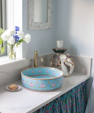 A ceramic sink decorated with blue and pink floral folk patterns