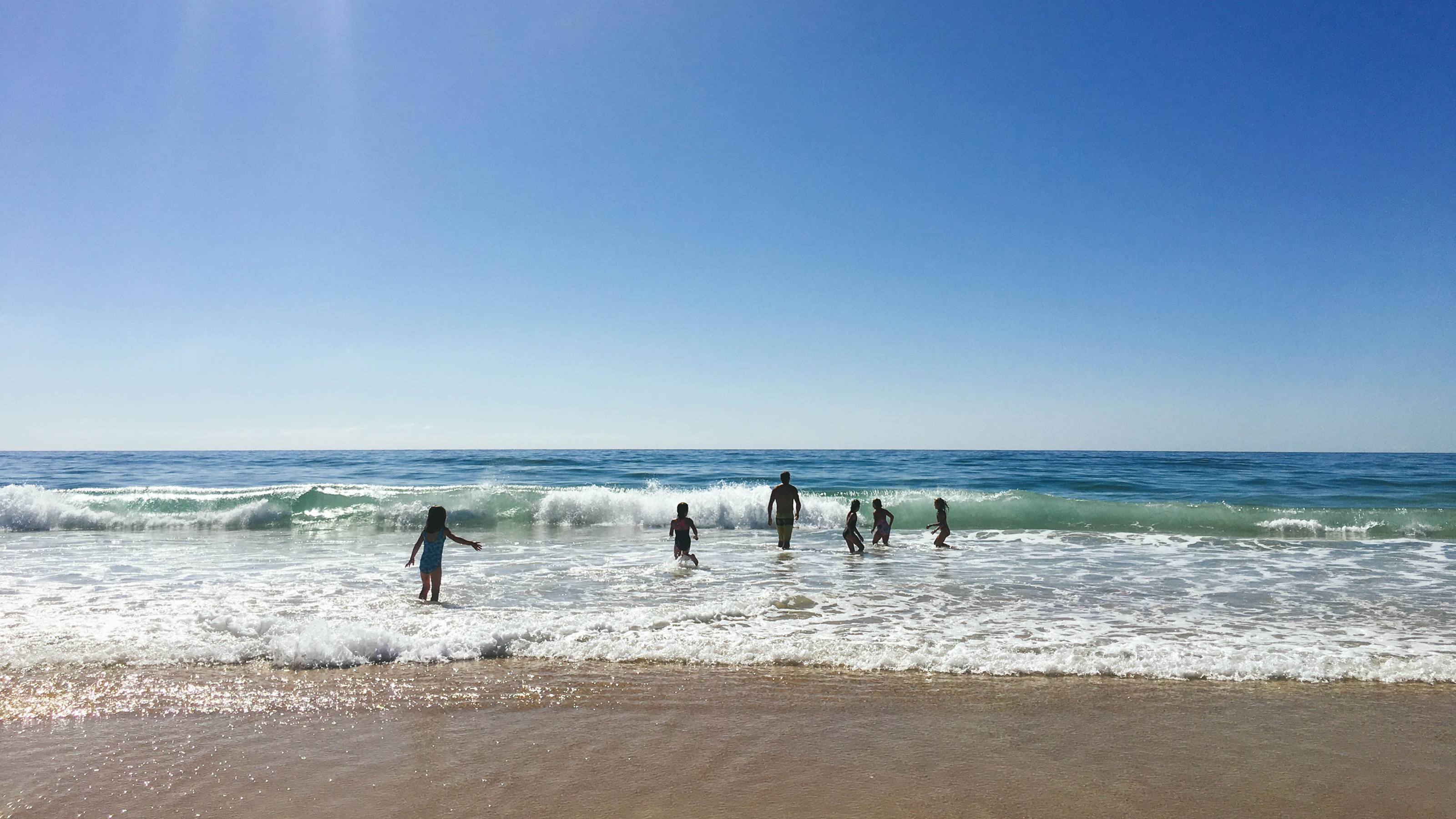 A family plays in the waves at a beach.