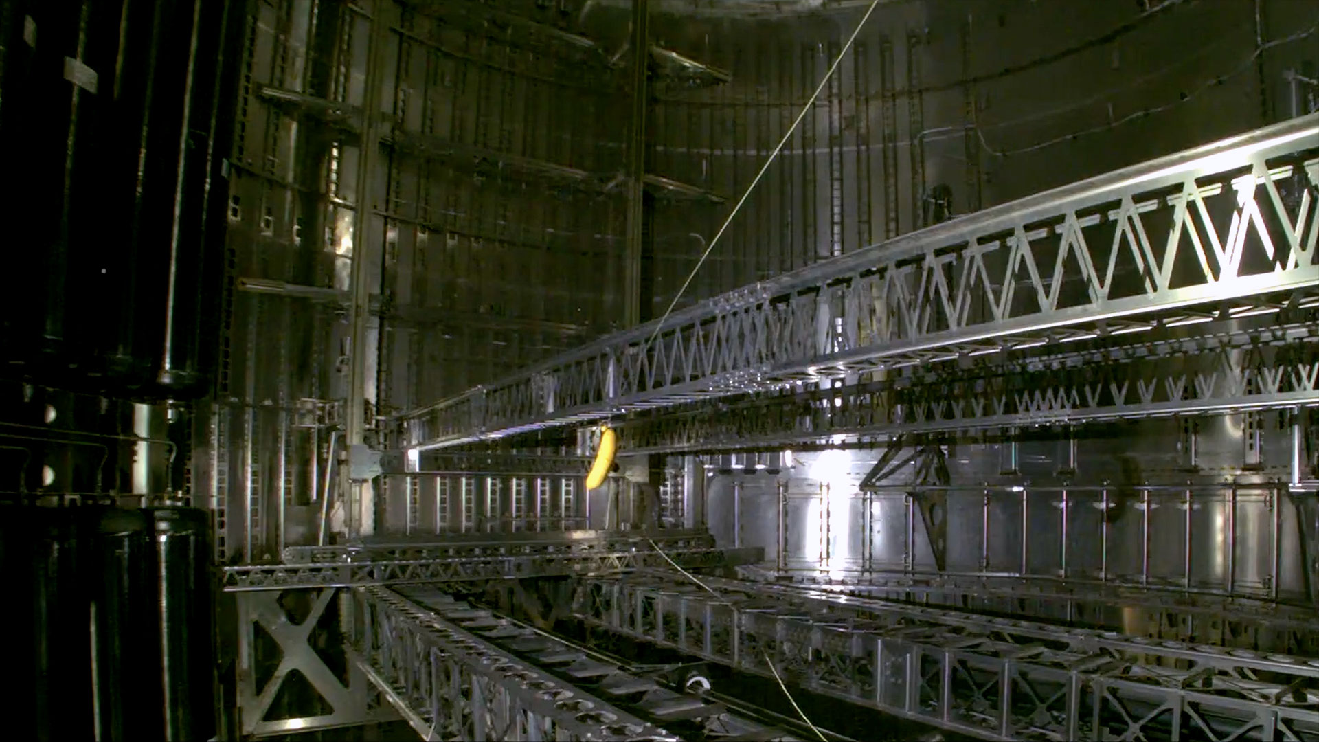 A toy banana floats at the end of its ropes in the cargo bay of a SpaceX spaceship.