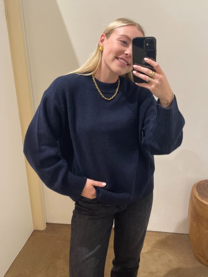 Woman wears navy crew neck cashmere jumper from Reformation and black jeans