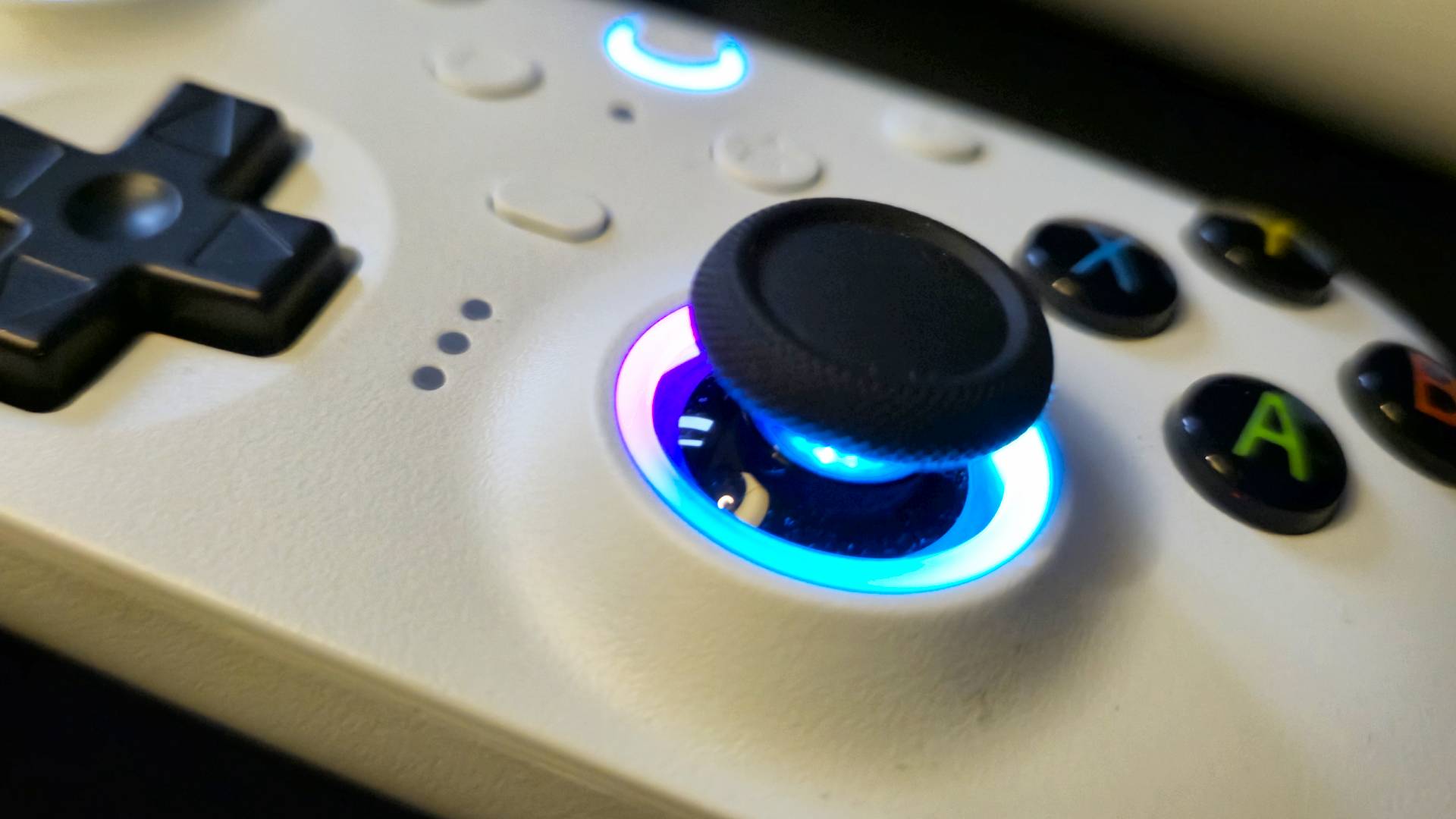 Close up of a ring of RGB lighting around the stick of a white wireless controller.