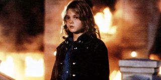 Firestarter Drew Barrymore stands in front of a burning building