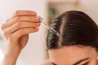 a woman applying oil to her scalp