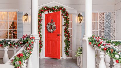 christmas porch decor: red front door with wreath and garland
