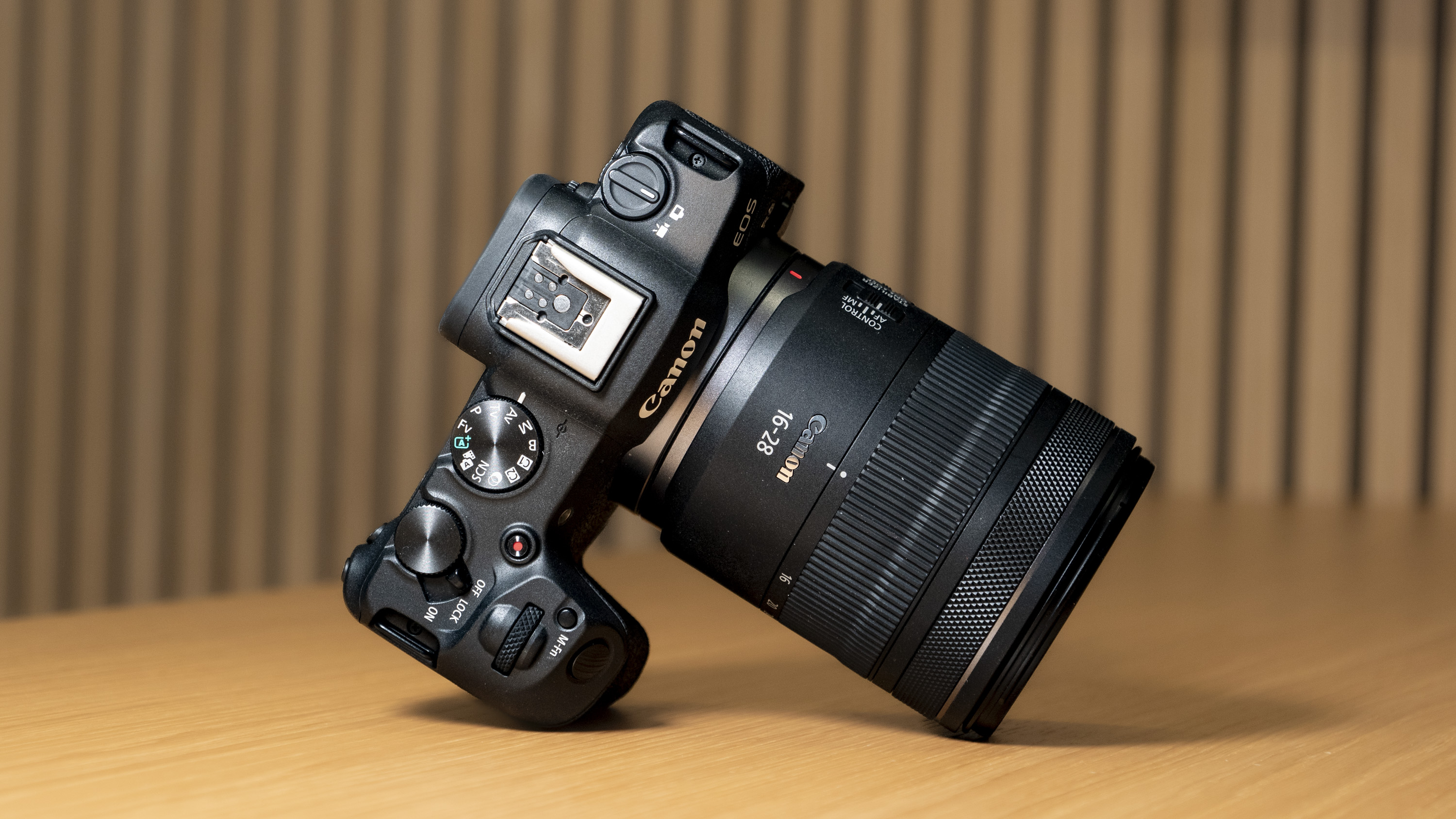 Canon RF 16-28mm F2.8 IS STM lens attached to the Canon EOS R8, resting on a wooden table.