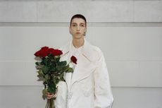 Man in Simone Rocha menswear white jacket holding flowers against wall