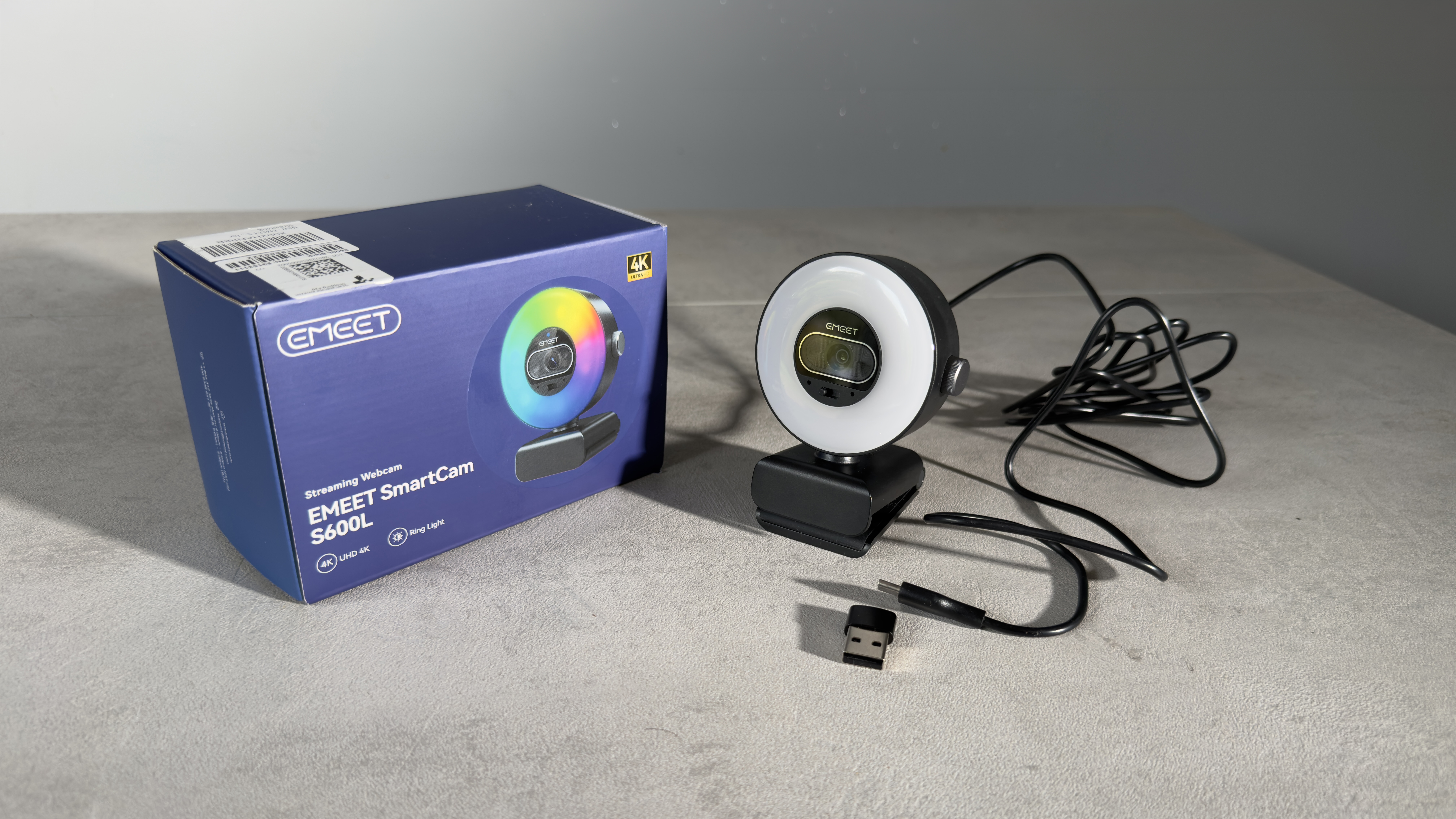 The EMEET SmartCam S600L webcam, USB cable and adapter displayed beside the retail box.