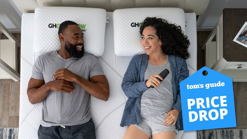 A bird&#039;s eye view of a man and woman lying on a GhostBed Massage Foam Mattress. In the bottom right, a Tom&#039;s Guide Price Drop deals graphic