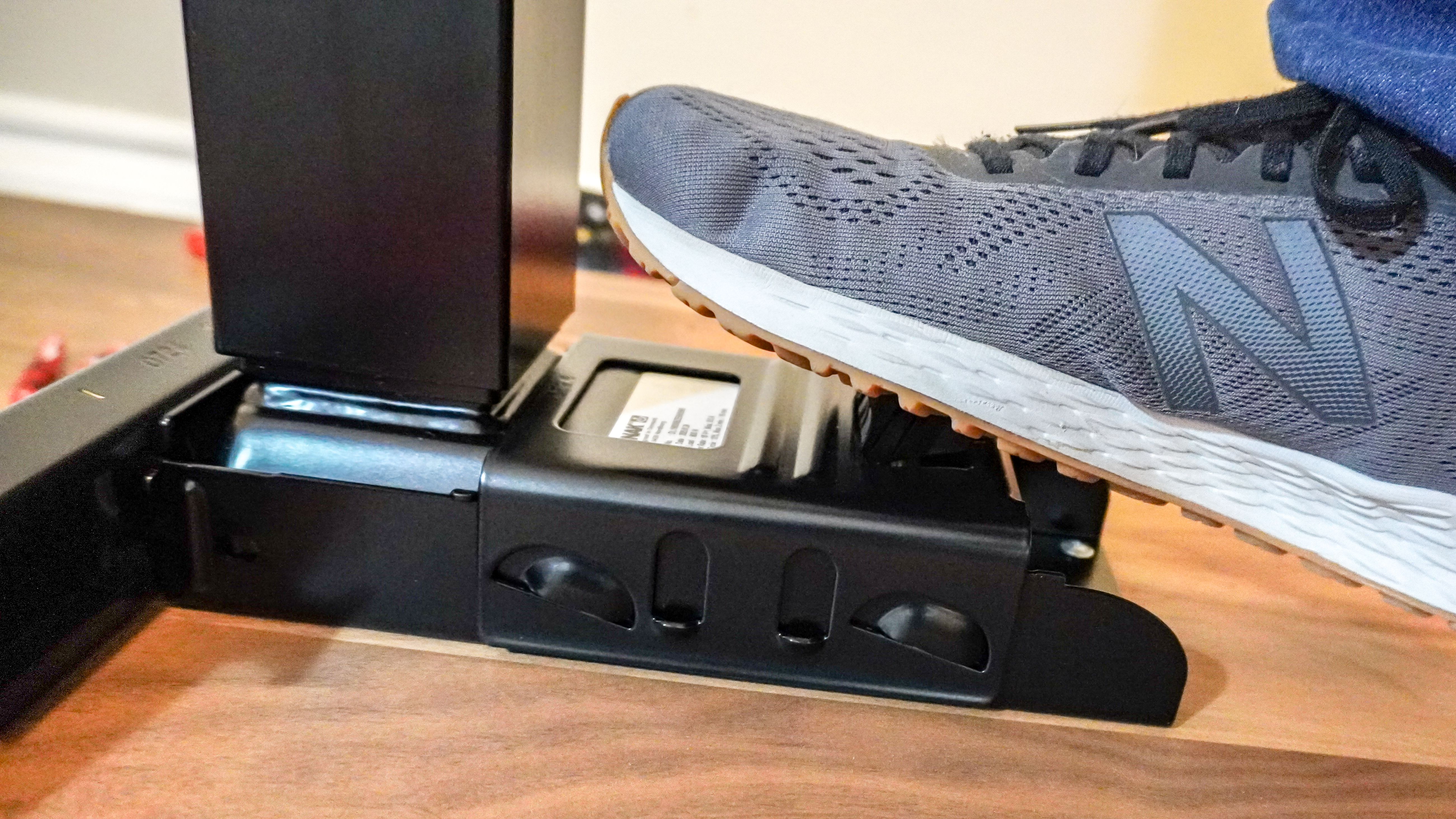 A person using their foot to snap the Oakywood Standing Desk Pro's legs into place