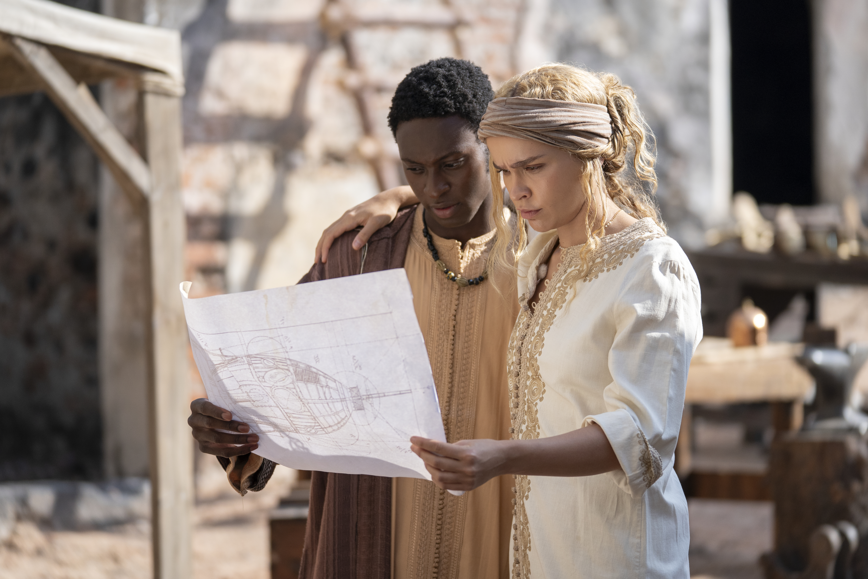 A man and a woman hold each other while looking at a blueprint, in 'Washington Black.'