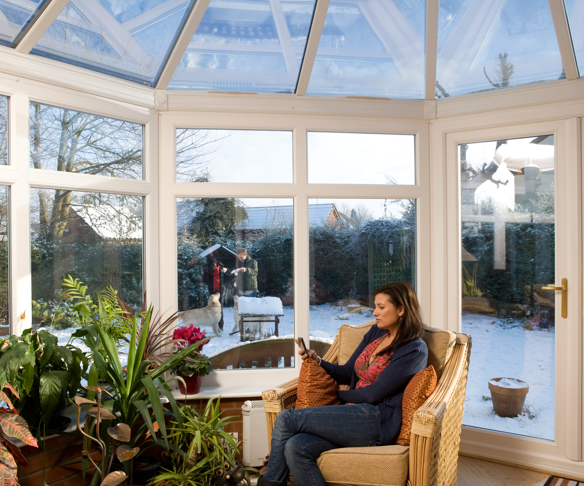 woman sat inside conservatory with snow covering ground outside