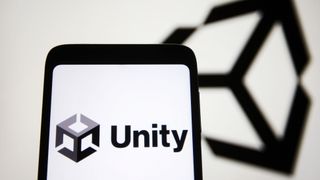 The Unity logo on a phone in front of the Unity logo on a wall.