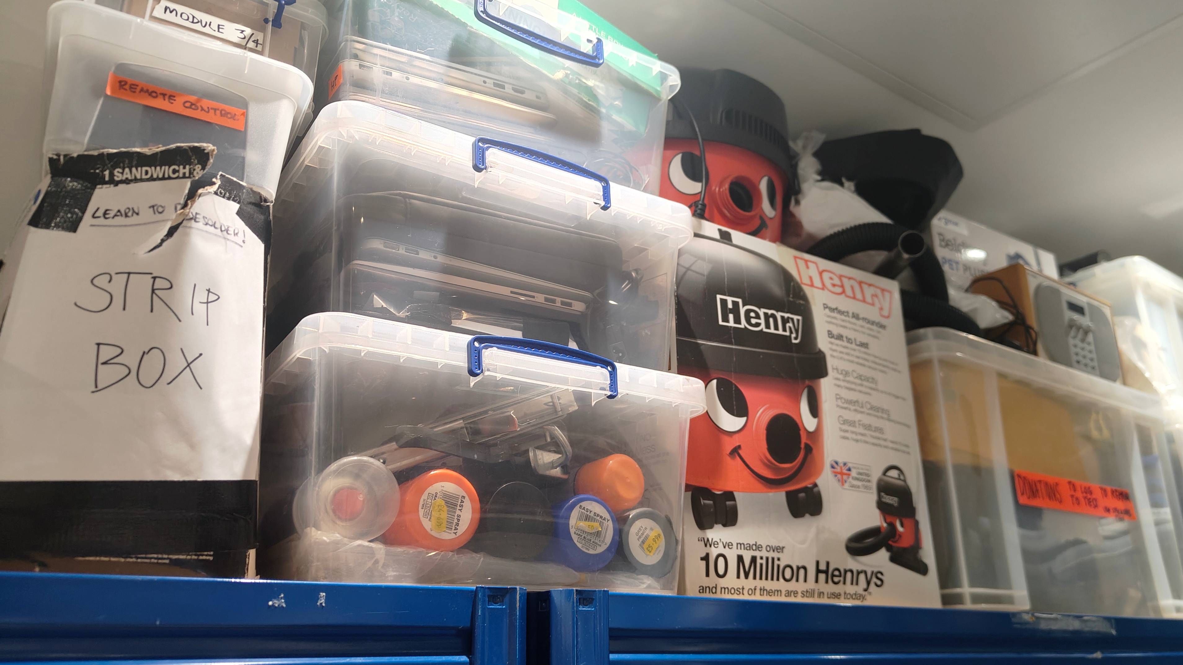 A shelf full of boxes of broken gadgets.