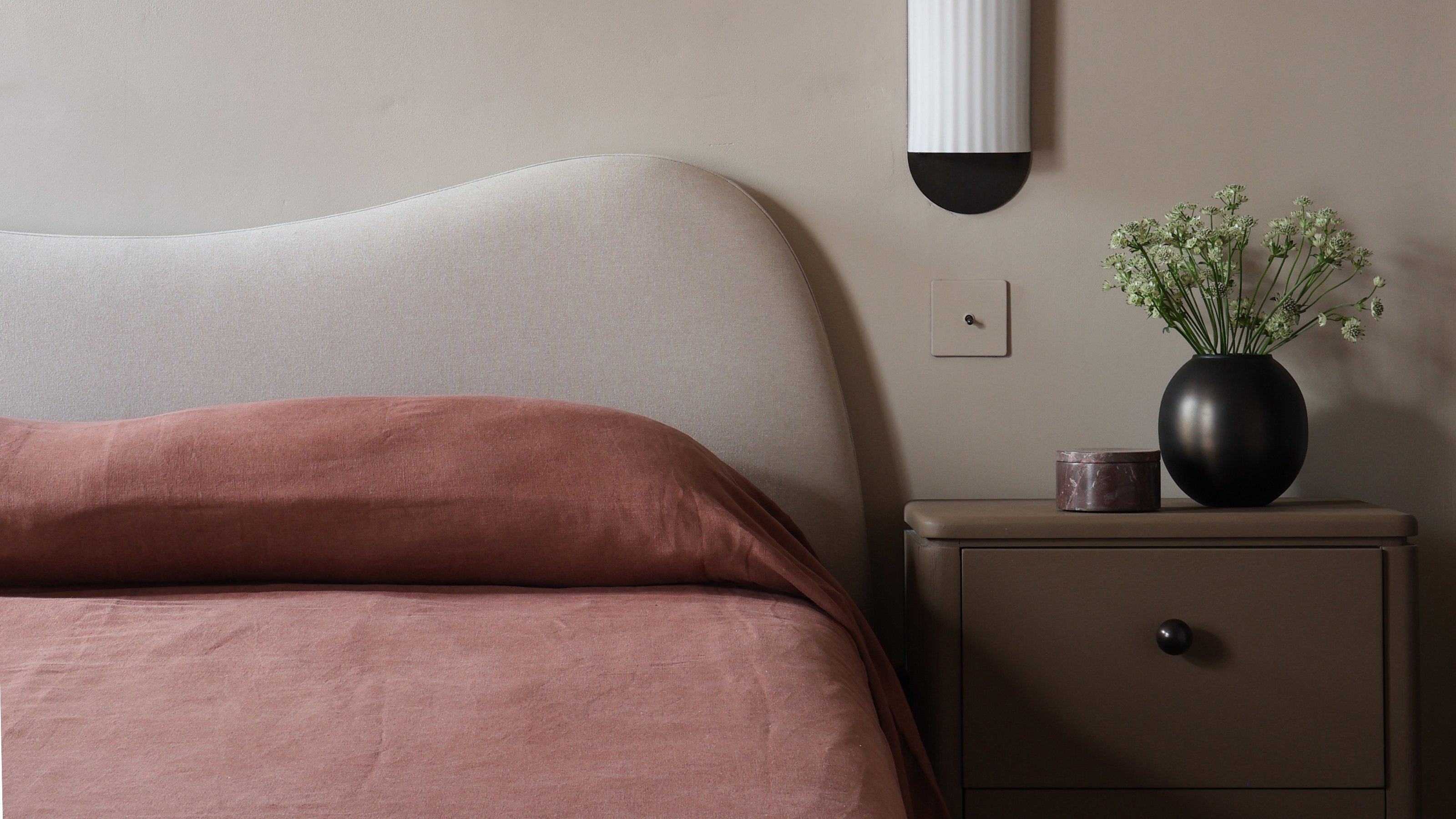 a wavy headboard with red linen sheets on the bed
