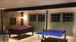 A converted garage with layered lighting and a games room inside