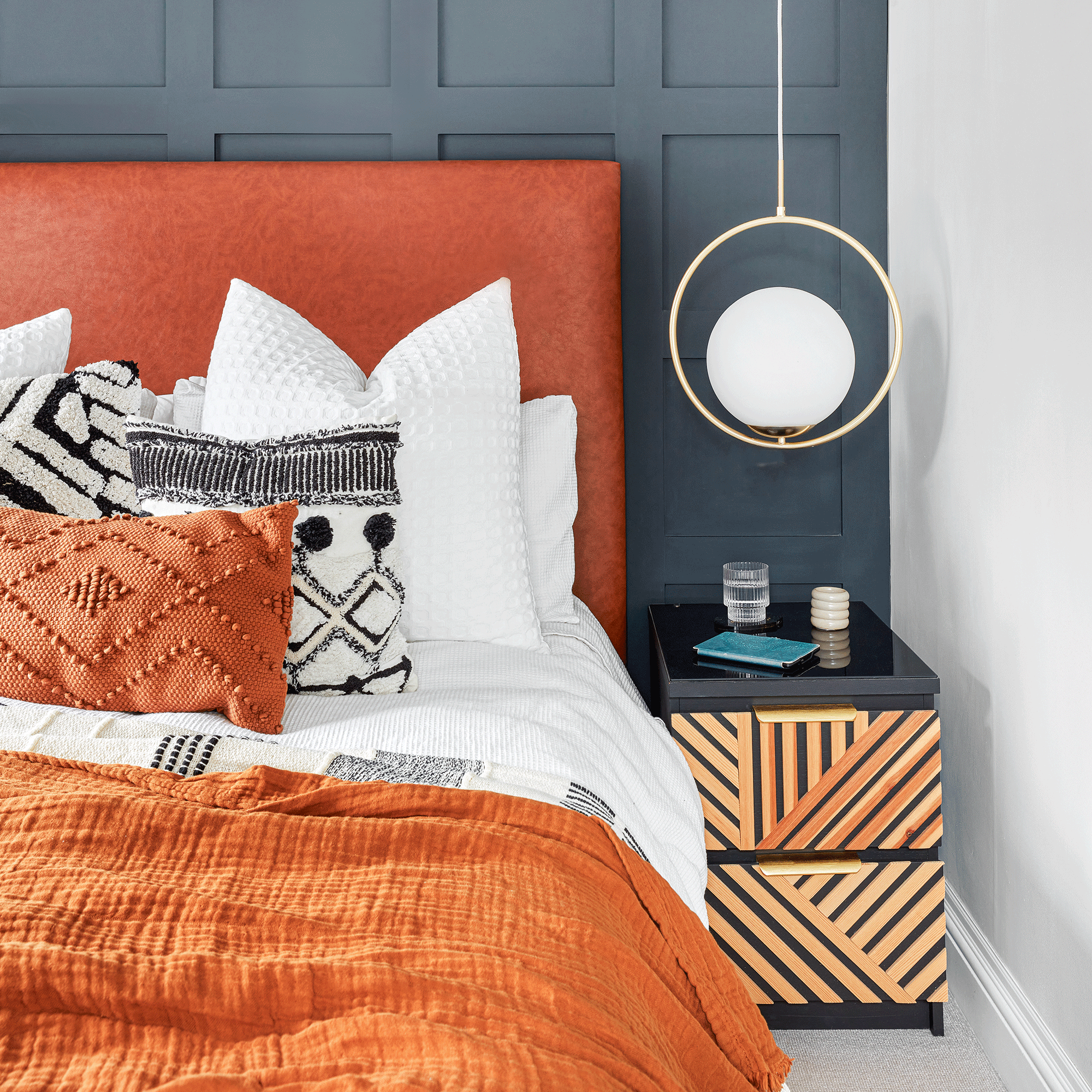 Blue panelled wall with orange headboard and bedding