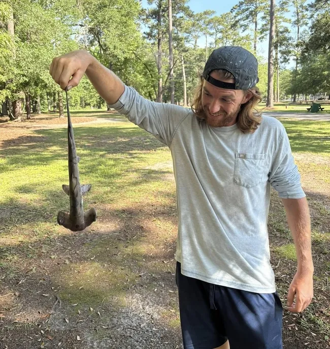 Jonathan Marlowe holding the hammerhead ⁤shark that​ fell on the ​disc golf course