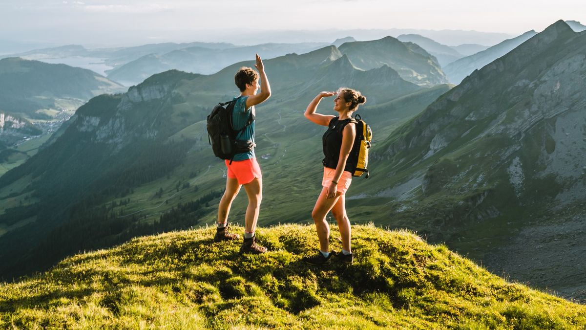 Two trail runners high-fiving on a mountain top