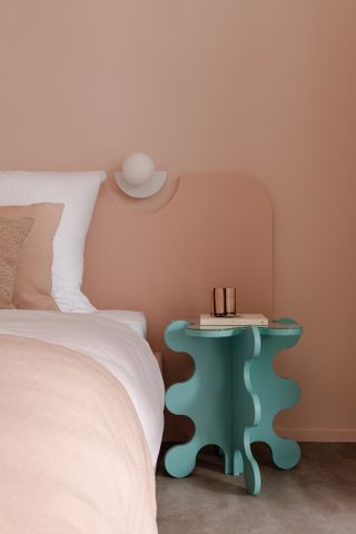 A bedroom with pink walls and a turquoise stool