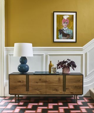 vivid yellow hallway with wooden sideboard and geometric tiled floor